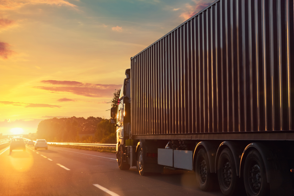 Sunset view of a cargo truck on the highway symbolizing reliable drayage services in Japan